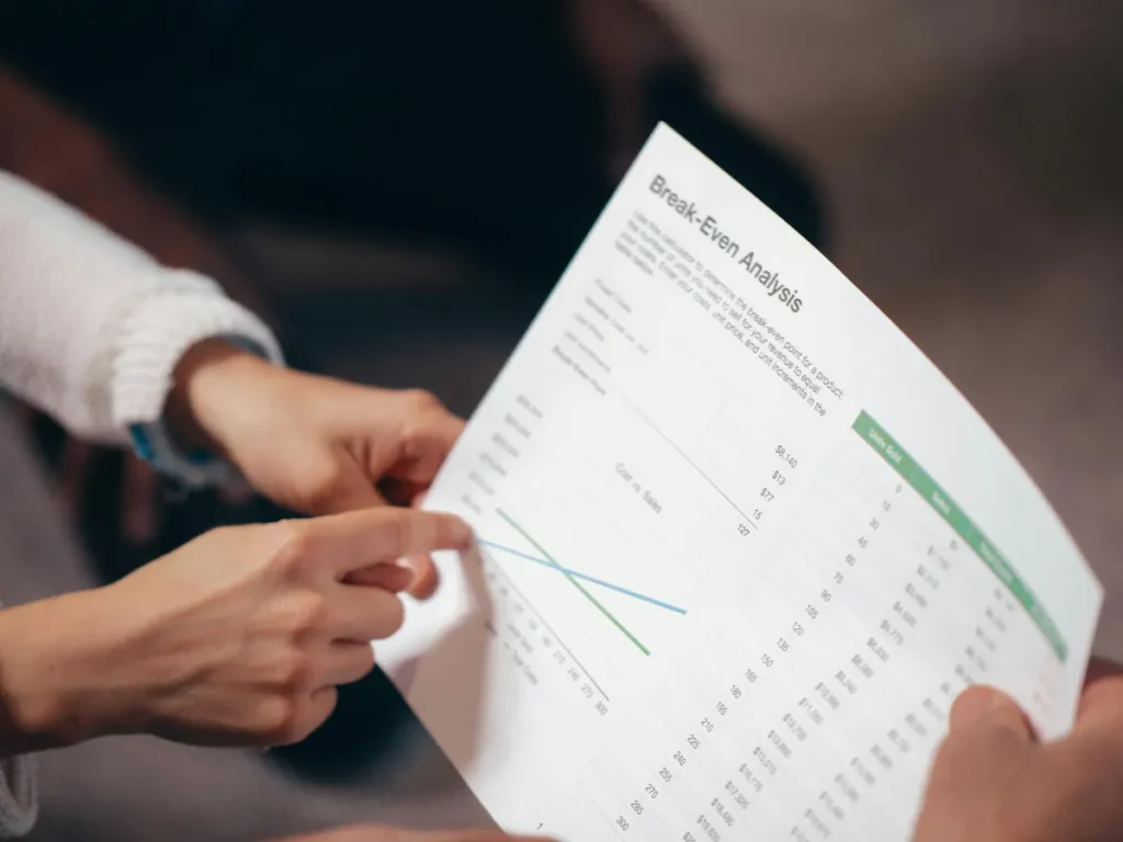 Tangan mendiskusikan dokumen analisis break even point dalam rapat bisnis