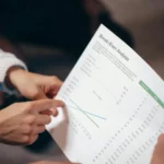 Tangan mendiskusikan dokumen analisis break even point dalam rapat bisnis